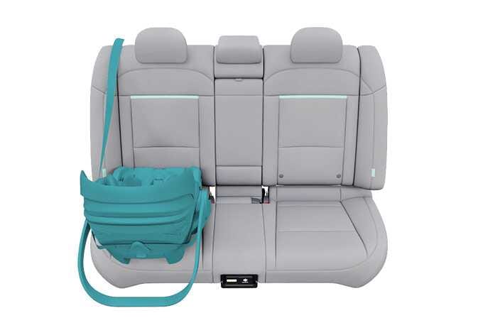 2026 Kia Tasman rearward-facing child restraint system image. A child safety seat highlighted in teal is installed on the rear seat, facing the rear of the vehicle. The seat belt, also highlighted in teal, is shown securing the child restraint system. Explains the correct orientation and placement of a rearward-facing child restraint system.
