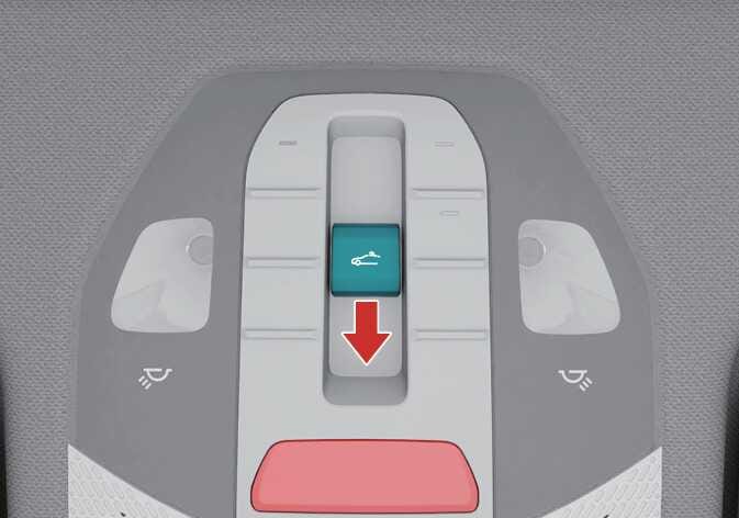 2026 Kia Tasman sunroof control switch image. The sunroof control lever on the overhead console is highlighted in teal. A red arrow points downwards, indicating the direction to move the lever. This describes the function of resetting the sunroof.