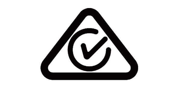 2026 Kia Tasman Regulatory Compliance Mark icon. The icon consists of a black triangle with rounded corners enclosing a circle with a check mark inside. It indicates compliance with applicable regulatory standards.