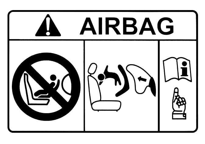 2026 Kia Tasman airbag warning label image. The label features 'AIRBAG' text with a warning triangle. A prohibition symbol depicts a rear-facing child restraint on a seat with a deploying airbag, and a central graphic illustrates the airbag striking the child seat. An open manual icon with a pointing hand instructs users to read the manual. This warns against using rear-facing child restraints in the front passenger seat.