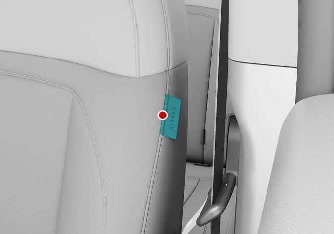 2026 Kia Tasman side air bag location image. A close-up of the front seat backrest shows an 'AIRBAG' label on the side seam, highlighted in teal. A red dot points to the label, explaining the location of the side air bag installed in the seat.