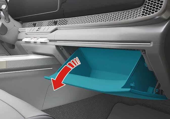 2026 Kia Tasman glove box operation image. The glove box door is highlighted in teal, and a thick red arrow points downward to indicate the opening direction. This explains the function of opening the glove box by pulling the handle.