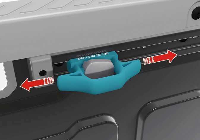 2026 Kia Tasman rail and cleat adjustment image. A teal-highlighted cleat with the text 'MAX LOAD 250 LBS' is shown on the rail. Red arrows pointing left and right indicate the sliding direction. Describes the function of moving the cleat to the desired position along the rail.
