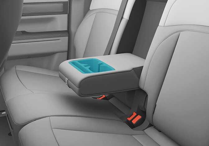 2026 Kia Tasman rear seat cup holder image. The center armrest is folded down between the rear seats, and the cup holder section is highlighted in cyan. This explains the location of the cup holders integrated into the rear seat armrest.