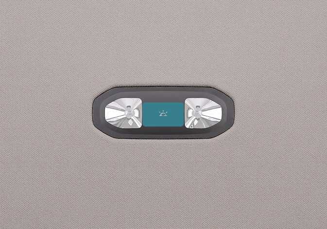 2026 Kia Tasman room lamp image. The overhead console is shown with a central button highlighted in teal between two lights. The button features a lamp icon. Describes the function of turning on the room lamp or adjusting the brightness by pressing the button.