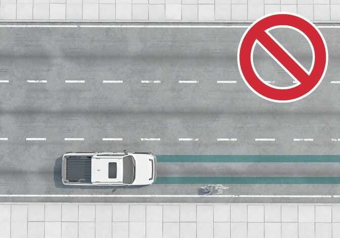 2026 Kia Tasman Forward Collision-Avoidance Assist limitation image. A top-down view shows the white vehicle and a cyclist in the adjacent lane, with the road highlighted in teal. A large red prohibition symbol is displayed. Explains the limitations regarding situations where the system does not operate.