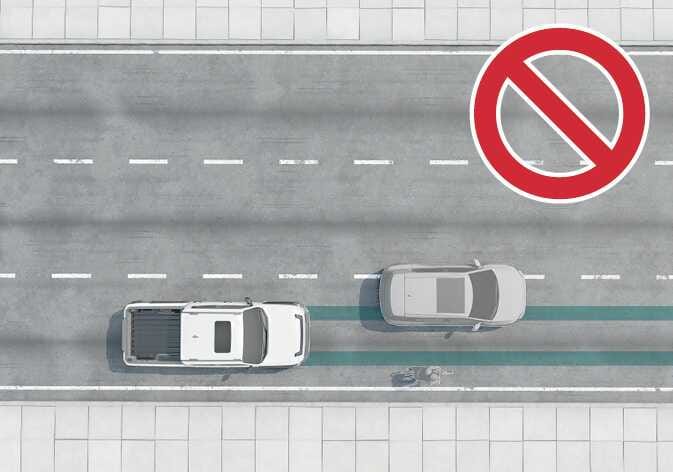2026 Kia Tasman Forward Collision-Avoidance Assist limitation image. A top-down view shows the white vehicle with a teal-highlighted detection path projecting forward. A silver vehicle is positioned in the adjacent lane, outside the highlighted area. A red prohibition symbol indicates that the system does not detect vehicles in adjacent lanes.