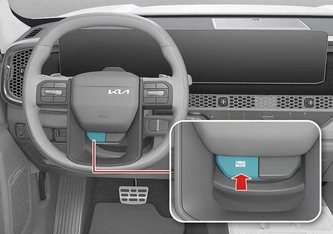 2026 Kia Tasman steering wheel DRIVE MODE button image. A magnified view highlights the 'DRIVE MODE' button on the lower left spoke in teal. A red arrow points upward to indicate the pressing operation. This explains the function of pressing and holding the button to activate TOW mode.
