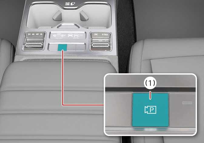2026 Kia Tasman Parking/View button image. The image shows the center console with the Parking/View button highlighted in teal. A red line connects the button to a magnified view labeled as (1), which features a camera icon with the letter 'P'. Explains the function of turning on the Rear View Monitor by pressing the button.