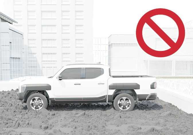 2026 Kia Tasman Remote Smart Parking Assist limitation image. A white pickup truck is shown on deep mud or uneven ground, marked with a large red prohibition symbol. Explains the limitation of operating the function on uneven roads or rough terrain.