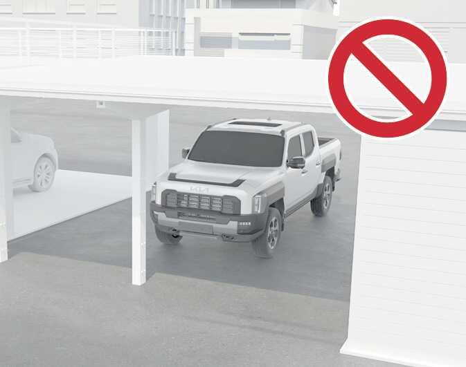 2026 Kia Tasman image showing a limitation of Remote Smart Parking Assist. A white pickup truck is positioned under a carport with pillars, overlaid with a large red prohibition symbol. This explains that the function may be limited in parking spaces with narrow pillars or overhead structures.