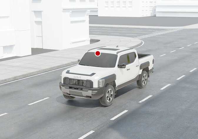 2026 Kia Tasman High Beam Assist detecting sensor location image. A red dot on the upper center of the windshield indicates the position of the front view camera. Explains the location of the sensor used to detect ambient light for the High Beam Assist function.