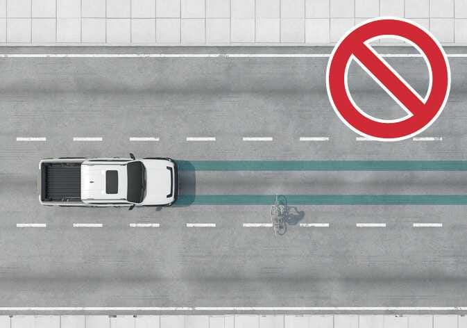 2026 Kia Tasman Forward Collision-Avoidance Assist limitation image. A top-down view shows a pickup truck and a cyclist in the adjacent lane highlighted in cyan, with a red prohibition symbol. Explains that the system does not detect targets in adjacent lanes.
