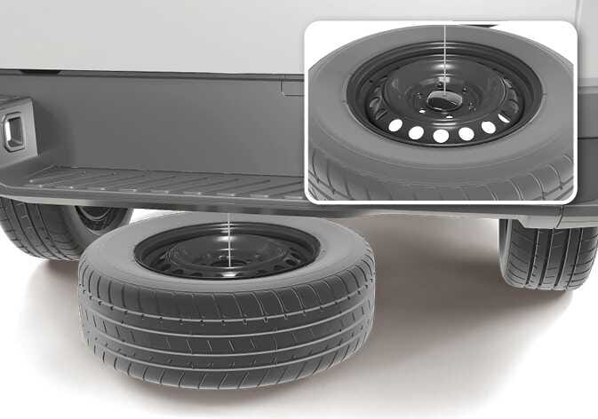 2026 Kia Tasman spare tire and retainer image. The spare tire lies flat on the ground under the rear bumper, connected by a cable. A detailed inset view shows the retainer plate seated in the wheel's center hub. Explains the state of the spare tire and retainer connection after being lowered.