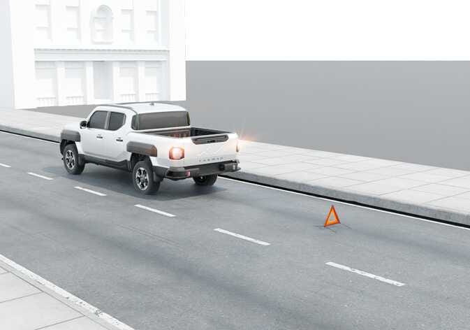2026 Kia Tasman hazard warning flasher image. The vehicle is parked with orange hazard lights blinking and a warning triangle placed on the road behind it. This illustrates safety measures before changing a tire.