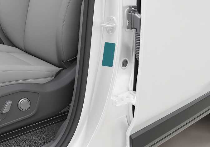 2026 Kia Tasman vehicle certification label location image. A rectangular label attached to the center pillar is highlighted in teal. Explains the location of the label that provides the vehicle identification number (VIN).