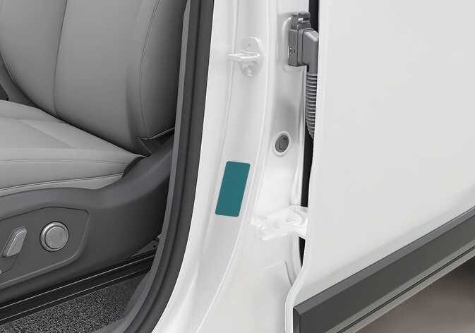 2026 Kia Tasman tire specification and pressure label image. The image shows the driver's side center pillar with the door open, where a rectangular label attached to the pillar is highlighted in teal. It explains the location of the tire label that provides recommended tire pressures.