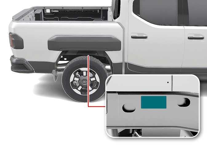 2026 Kia Tasman Vehicle Identification Number (VIN) location image. A red line points from the chassis frame behind the rear left wheel to a magnified inset, showing the VIN location highlighted in teal. Explains the location of the VIN stamped on the frame.