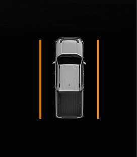 2026 Kia Tasman Side Parking Distance Warning infotainment display image. A top-down view of the silver vehicle features vertical orange lines along both sides on a black background. This explains the warning displayed when an object is detected within 30 to 60 cm (12 to 24 in) from the side.
