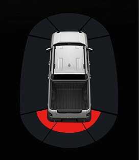 2026 Kia Tasman Reverse Parking Distance Warning image. A top-down view of the vehicle shows the innermost arc behind the rear bumper highlighted in red. This indicates an object is detected within 30 cm (12 in), triggering a continuous warning sound.