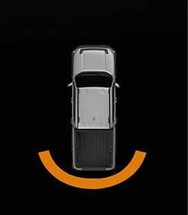 2026 Kia Tasman Reverse Parking Distance Warning image. A top-down view of the vehicle is shown with an orange curved line behind the rear bumper. This indicates that an object is detected within 30 to 60 cm (12 to 24 in) from the rear.