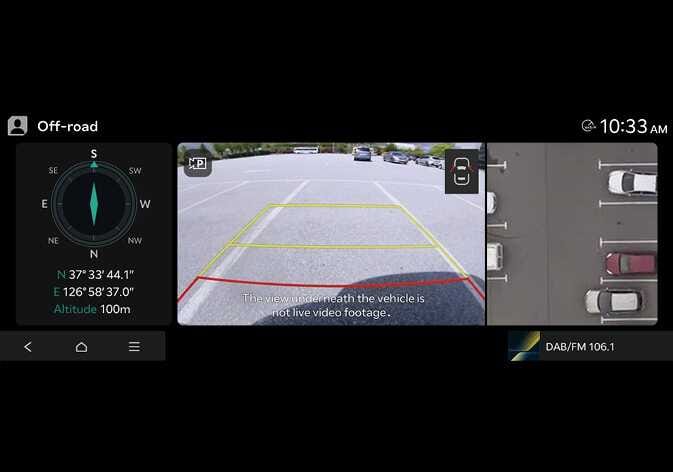 2026 Kia Tasman Ground View Monitor image. The Off-road screen displays a compass on the left, a central ground view with the text \'The view underneath the vehicle is not live video footage,\' and a top-down view on the right. This describes the Ground View Monitor layout.