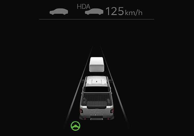 2026 Kia Tasman Highway Driving Assist display image. The instrument cluster screen displays 'HDA' and the set speed '125 km/h' at the top. A white block representing a vehicle ahead is shown in front of the host vehicle between lane lines, with a green steering wheel icon at the bottom. Explains the function of indicating the Highway Driving Assist operation status and vehicle detection.