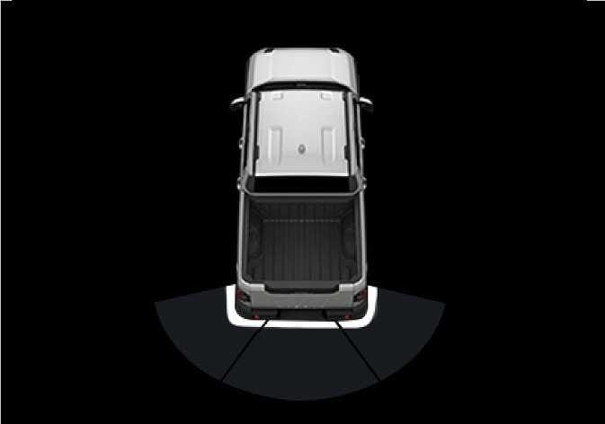 2026 Kia Tasman Reverse Parking Collision-Avoidance Assist operation image. A top-down view of the vehicle displays a fan-shaped area behind the rear bumper. This illustrates the line that appears behind the vehicle image in the instrument cluster when the function activates.