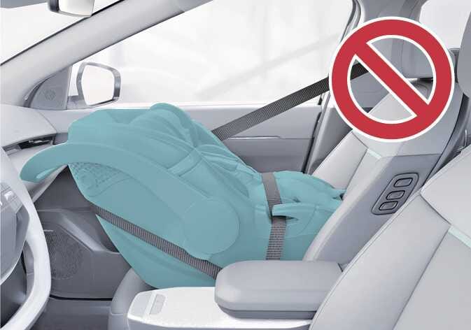 2026 기아 타스만 동승석 어린이 보조 시트 장착 금지 이미지입니다. 차량 진행 반대 방향으로 설치된 청록색으로 강조된 어린이 보조 시트 위에 붉은색 금지 기호가 크게 표시되어 있습니다. 에어백 작동 시 위험하므로 동승석에 어린이 보조 시트 설치를 금지함을 설명합니다.
