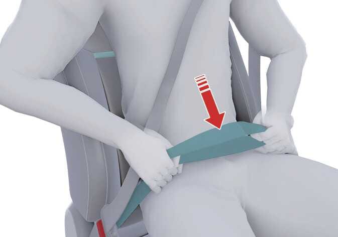 2026 기아 타스만 안전벨트 올바른 착용 위치 이미지입니다. 탑승자가 좌석에 앉아 안전벨트를 착용하고 있으며, 청록색으로 강조된 골반띠 위로 아래 방향을 가리키는 붉은색 화살표가 표시되어 있습니다. 골반띠를 허리가 아닌 골반 부분에 최대한 낮게 위치시켜 착용해야 하는 올바른 방법을 설명합니다.