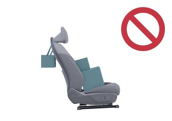 2026 기아 타스만 동승석 승객 구분 시스템 작동 조건 이미지입니다. 동승석 시트의 헤드레스트 뒤쪽에 청록색으로 강조된 물건이 걸려 있고, 등받이 뒤와 시트 쿠션 위에도 청록색 상자가 놓여 있습니다. 우측 상단에는 붉은색 금지 기호가 크게 표시되어 있습니다. 시트 주변에 물건을 두거나 걸어두는 행위가 시스템 작동을 방해할 수 있음을 알리는 기능을 설명합니다.