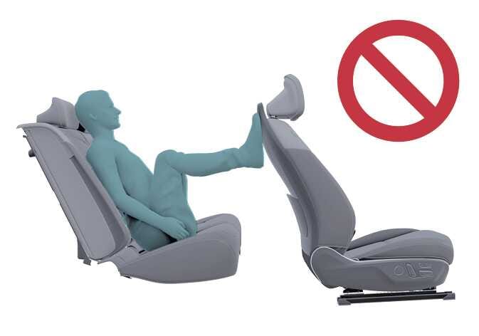 2026 기아 타스만 동승석 부적절한 착석 자세 이미지입니다. 청록색으로 강조된 탑승자가 대시보드에 발을 올리고 있는 모습과 우측 상단에 붉은색 금지 기호가 표시되어 있습니다. 승객 구분 시스템의 정상 작동을 위해 바르지 않은 자세를 금지하는 내용을 설명합니다.