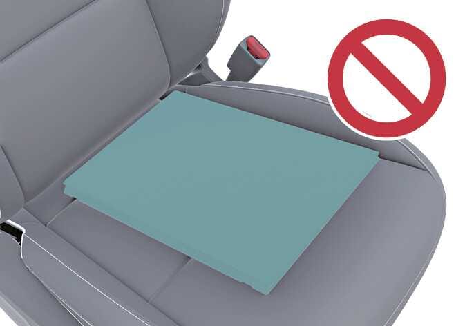 2026 기아 타스만 동승석 시트 쿠션 사용 금지 이미지입니다. 동승석 시트 엉덩이 받침 부분에 청록색으로 강조된 쿠션이 놓여 있으며, 우측 상단에 붉은색 금지 기호가 크게 표시되어 있습니다. 승객 구분 시스템(ODS)의 정상적인 작동을 위해 시트 표면을 덮는 쿠션 사용을 금지하는 주의사항을 설명합니다.