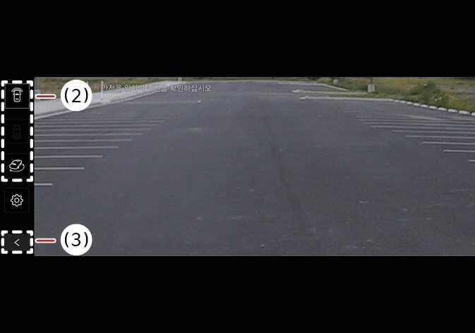 2026 기아 타스만 서라운드 뷰 모니터 화면 이미지입니다. 주차장 영상이 표시된 화면 좌측에 세로로 배치된 뷰 전환 버튼(2)과 하단의 뒤로 가기 버튼(3)을 붉은색 선으로 가리키고 있습니다. 버튼을 눌러 원하는 카메라 뷰로 전환하거나 이전 화면으로 이동하는 기능을 설명합니다.