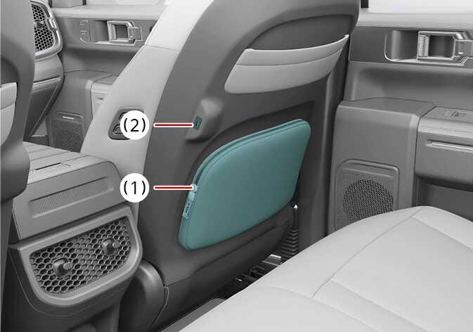 2026 기아 타스만 좌석 등받이 포켓 및 USB 충전 단자 이미지입니다. 앞좌석 등받이 뒤편의 수납 포켓(1)과 등받이 측면의 USB 충전 단자(2)가 청록색으로 강조되어 있습니다. 뒷좌석 승객이 책이나 지도를 보관하거나 휴대기기를 충전하는 기능을 설명합니다.