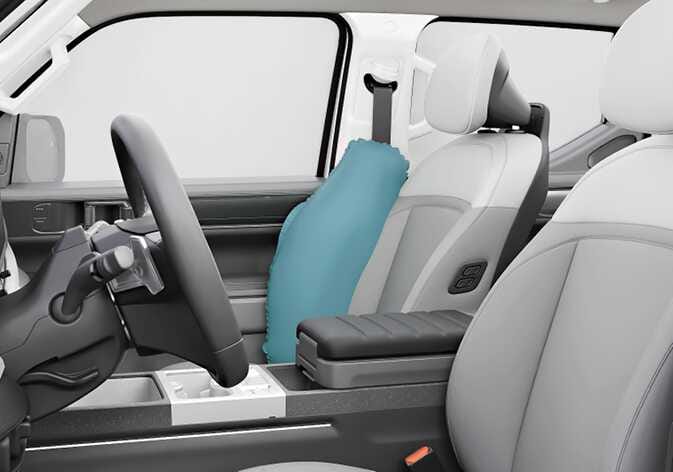 2026 기아 타스만 앞좌석 센터 사이드 에어백 이미지입니다. 운전석 우측 측면에서 청록색으로 강조된 에어백이 팽창하여 운전석과 콘솔 박스 위쪽 공간을 채우고 있는 모습을 보여줍니다. 사고 발생 시 운전자와 동승자 간의 충돌을 방지하고 내장 부품과의 충돌을 줄여주는 기능을 설명합니다.