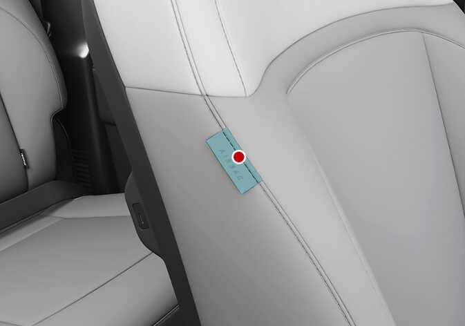 2026 기아 타스만 앞좌석 센터 사이드 에어백 장착 위치 이미지입니다. 운전석 시트 측면 봉제선에 부착된 'AIRBAG' 라벨이 청록색으로 강조되어 있으며, 빨간색 점이 해당 위치를 지시하고 있습니다. 운전석 오른쪽에 내장되어 충돌 시 운전자와 동승자가 부딪히는 것을 방지하는 에어백의 위치를 설명합니다.