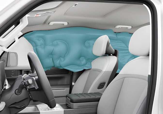 2026 기아 타스만 커튼 에어백 작동 이미지입니다. 차량 실내 측면 창문 전체를 덮으며 길게 팽창된 에어백이 청록색으로 강조되어 있습니다. 측면 충돌이나 전복 시 앞좌석과 뒷좌석 탑승자의 머리를 보호하는 기능을 설명합니다.