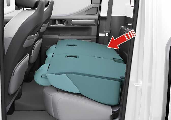 2026 기아 타스만 뒷좌석 폴딩 이미지입니다. 청록색으로 강조된 등받이가 시트 쿠션 위로 완전히 접힌 모습이며, 굵은 빨간색 화살표가 등받이가 접히는 방향을 가리키고 있습니다. 등받이를 앞으로 접어 적재 공간을 확보하는 기능을 설명합니다.