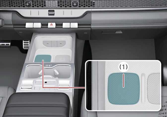 2026 기아 타스만 실내 인증 패드 이미지입니다. 센터 콘솔의 사각형 패드가 청록색으로 강조되어 있고, 붉은색 선으로 연결된 상세도에 (1)번으로 표시되어 있습니다. 실내 인증 패드(무선 충전 패드)(1)에 스마트폰을 접촉하여 디지털 키를 등록하는 위치를 설명합니다.