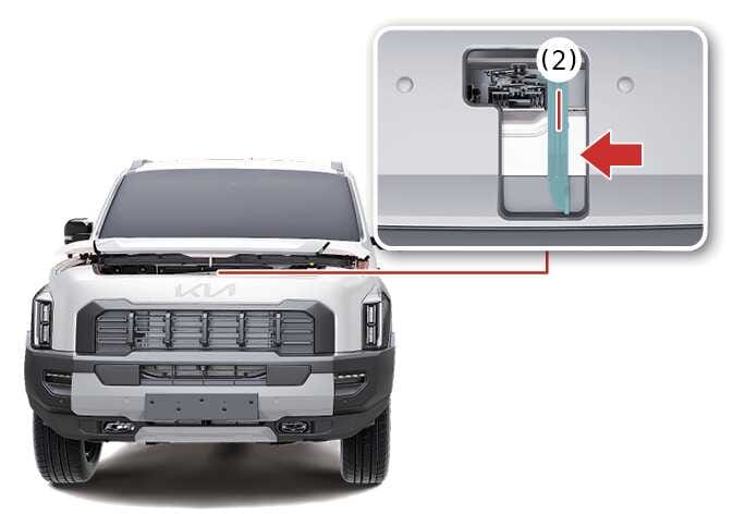 2026 기아 타스만 엔진 후드 2차 열림 레버 이미지입니다. 차량 전면부 후드 중앙 틈새를 확대한 상세도에 청록색으로 강조된 2차 열림 레버(2)와 왼쪽 방향을 가리키는 붉은색 화살표가 표시되어 있습니다. 레버를 화살표 방향으로 밀어 후드 잠금을 완전히 해제하고 여는 방법을 설명합니다.