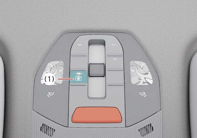 2026 기아 타스만 빌트인 캠 수동 녹화 버튼 이미지입니다. 오버헤드 콘솔 중앙에 위치한 조작부 중 카메라 아이콘이 표시된 버튼(1)이 청록색으로 강조되어 있습니다. 버튼을 눌러 운전자가 원하는 시점의 영상을 수동으로 녹화하는 기능을 설명합니다.