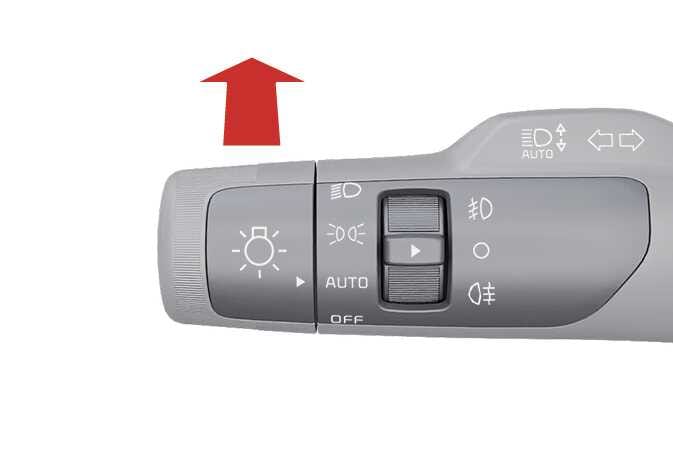2026 기아 타스만 조명 스위치 레버 이미지입니다. 레버 표면에 전조등, AUTO, 안개등 아이콘이 표시되어 있으며, 레버 상단에 굵은 붉은색 화살표가 계기판 방향인 위쪽을 가리키고 있습니다. 스위치를 밀어 주행빔을 켜는 조작 방법을 설명합니다.