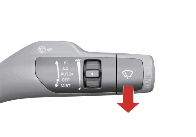 2026 기아 타스만 와이퍼 조작 레버 이미지입니다. 레버 표면에는 HI, LO, AUTO, OFF, MIST 문구와 와이퍼 아이콘이 표시되어 있습니다. 레버 끝부분 아래쪽에 위치한 굵은 빨간색 화살표가 아래 방향을 가리키며 조작 방법을 안내하고 있습니다. 레버를 운전자 방향으로 당겨 워셔액을 분출하고 와이퍼를 작동시키는 기능을 설명합니다.