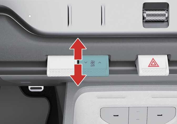 2026 기아 타스만 풍량 조절 레버 이미지입니다. 청록색으로 강조된 레버 표면에 팬 아이콘과 OFF 문구가 표시되어 있으며, 붉은색 수직 양방향 화살표가 레버의 조작 방향을 가리키고 있습니다. 레버를 위아래로 눌러 풍량을 조절하는 기능을 설명합니다.