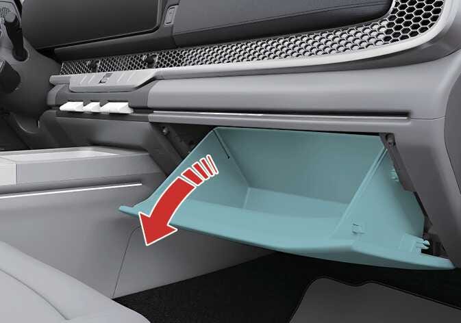 2026 기아 타스만 글로브박스 개방 이미지입니다. 청록색으로 강조된 글로브박스가 열려 있는 상태를 보여주며, 굵은 붉은색 굽은 화살표가 아래쪽으로 열리는 방향을 나타내고 있습니다. 레버를 조작하여 글로브박스를 여는 기능을 설명합니다.