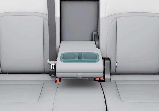 2026 기아 타스만 뒷좌석 컵 홀더 이미지입니다. 뒷좌석 중앙 암레스트가 아래로 내려와 있고, 암레스트에 위치한 컵 홀더가 청록색으로 강조되어 있습니다. 암레스트를 당겨 내려 컵 홀더를 사용하는 기능을 설명합니다.