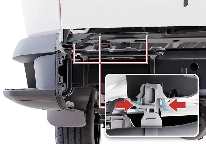 2026 기아 타스만 테일게이트 케이블 분리 이미지입니다. 뒷범퍼 하단의 케이블 장착 위치와, 청록색으로 강조된 클립의 고정 탭을 좌우 붉은색 화살표 방향으로 눌러 모으는 상세도가 포함되어 있습니다. 뒷범퍼 하단에 위치한 케이블을 분리하는 기능을 설명합니다.