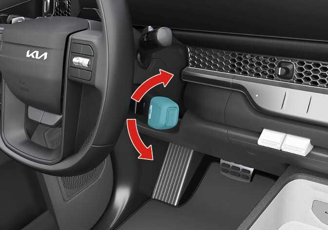 2026 기아 타스만 전자식 변속 레버 조작 이미지입니다. 스티어링 휠 우측에 위치한 변속 레버 손잡이가 청록색으로 강조되어 있으며, 굽은 붉은색 화살표가 레버의 회전 방향을 지시하고 있습니다. 브레이크를 밟고 레버를 앞뒤로 돌려 기어를 변속하는 작동 방법을 설명합니다.