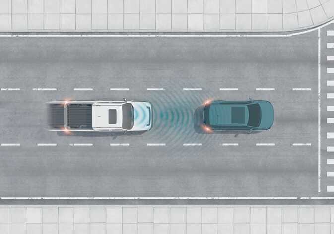 2026 기아 타스만 전방 충돌방지 보조 시스템 작동 이미지입니다. 도로 위를 주행 중인 흰색 차량 전면에서 청록색으로 강조된 센서 파동이 방출되어 앞서가는 짙은 색 차량을 감지하는 모습을 보여줍니다. 전방 차량을 인식하여 충돌 위험이 판단되면 운전자에게 경고하고 제동을 도와주는 기능을 설명합니다.